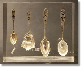 Store display of early  Disneyland sterling silver souvenir spoons encased in a solid acrylic block. Front image.