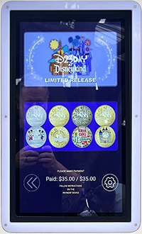 The first D23 Day at Disneyland medallion machine located outdoors, in Downtown Disney, near the Disneyland Monorail and the Star Wars Trading Post. The medallions have provisional numbers of button A. # 305 Mickey and Minnie 25th, button B. # 306 Disneyland Castle, button C. # 307 Trader Sam, and button D. # 308 Small World. 8-13-2026